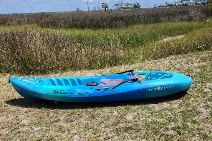 a blue boat sitting on top of a grass covered field